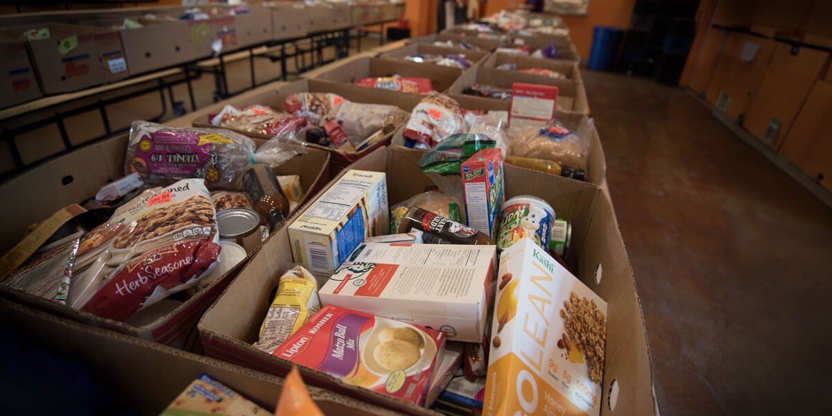 Cardboard boxes filled with assorted packaged food donations at a local food pantry.
